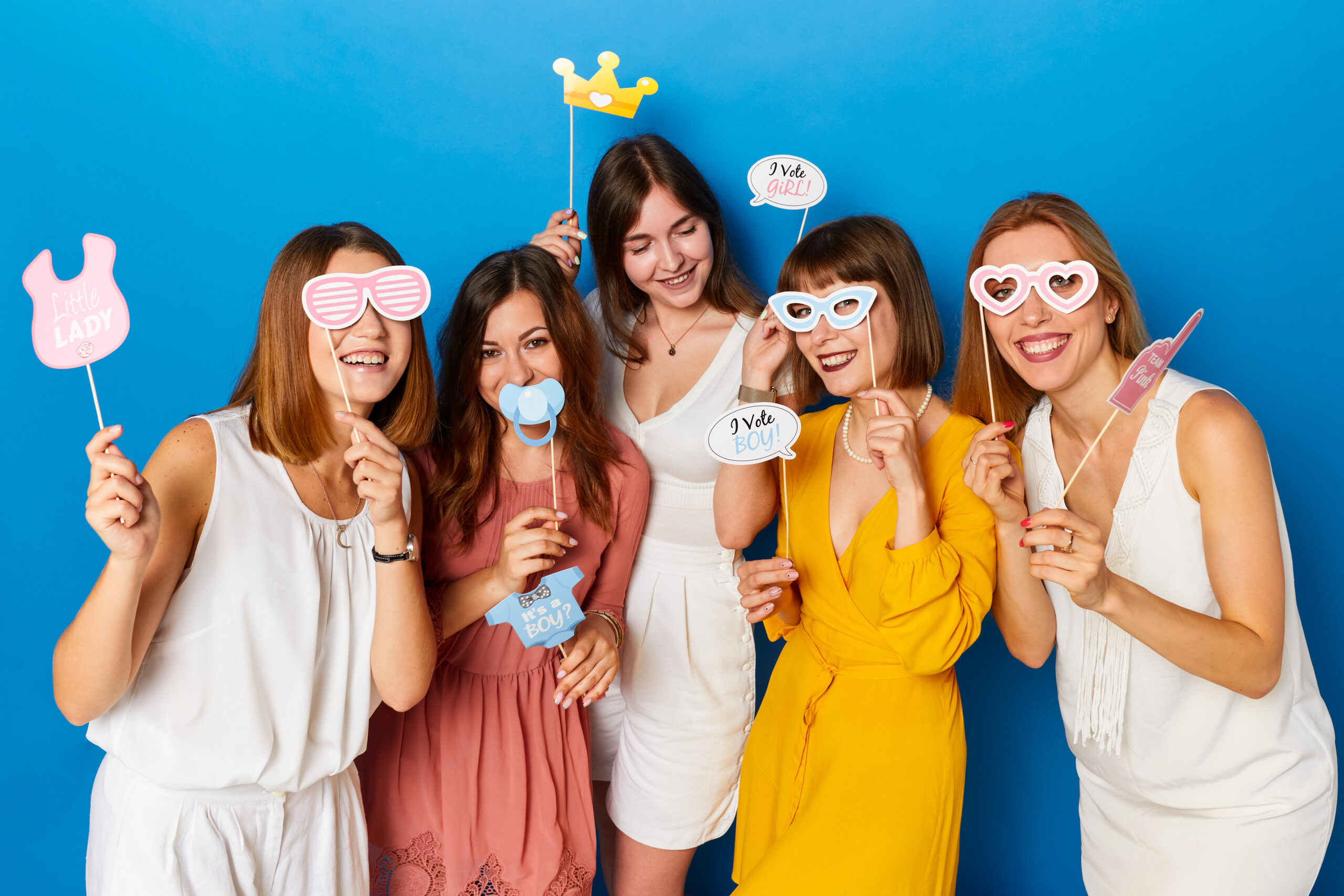 A group of happy females models, celebrated gender reveals envent, isolated blue background.